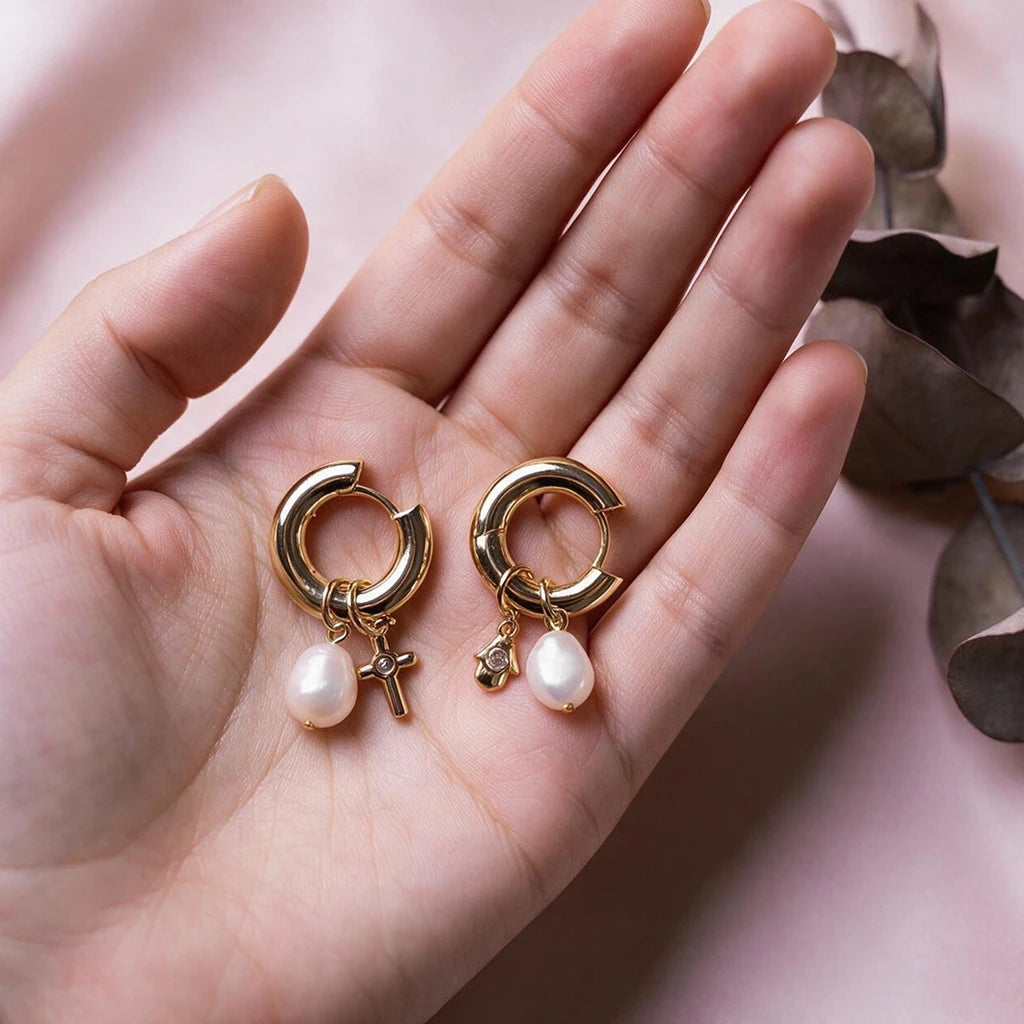 Charm hoop earrings held in an open palm for scale